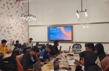 Students at a build night in a smaller room, laptops open around a shared table